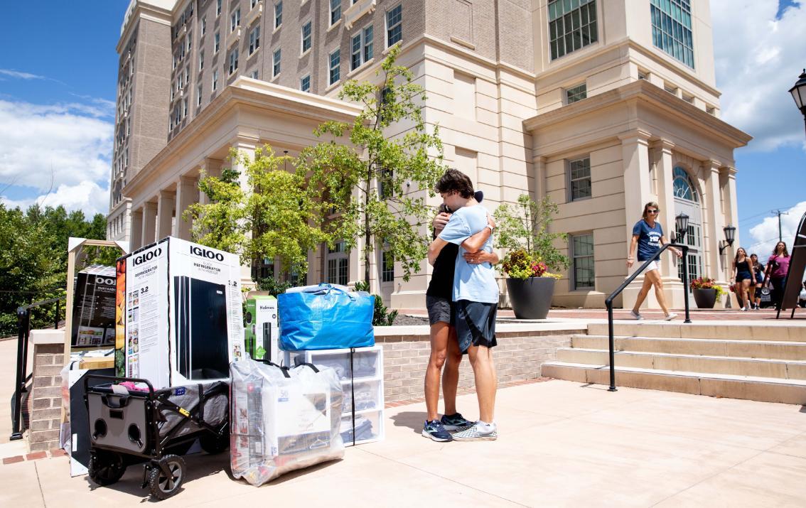 A couple hugging outside one of the high rise residence halls